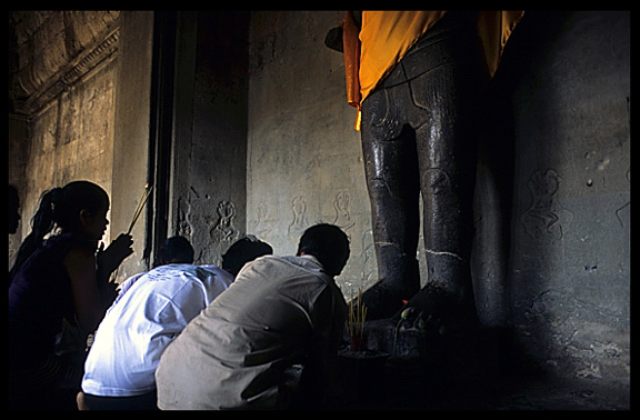 Praying before a Buddha statue inside Angkor Wat.