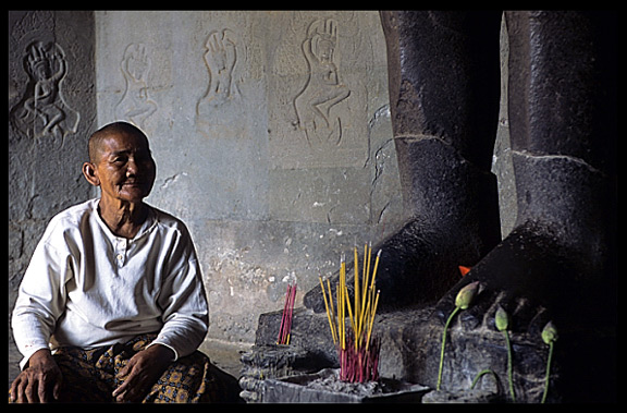 A Buddhist nun in front of a Buddha statue inside Angkor Wat.