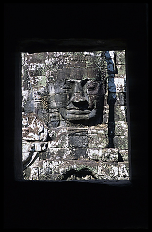 One of the smiling faces in the Bayons seen through a window.