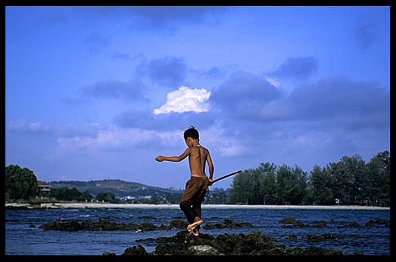 A Cambodian kid is fishing at a fishing community near Sihanoukville.