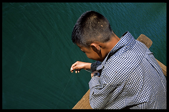 A boy is fishing in Boeng Yeak Lom with its circular crater-lake situated amid pristine jungle, Ban Lung, Cambodia