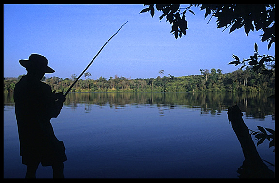 A fisherman at Boeng Yeak Lom with its circular crater-lake situated amid pristine jungle, Ban Lung, Cambodia
