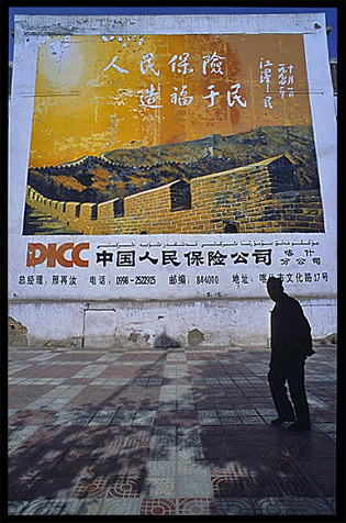 Silhouette of Uyghur man walking in front of a big advertisment. Kashgar, Xinjiang, China