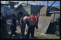 A man carries fresh camel meat at the Sunday Market. Hotan, Xinjiang, China