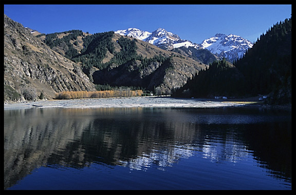 Heaven Pool or Heavenly Lake (Tian Chi) with snow-covered Tian Shan mountains in the distance. Urumqi, Xinjiang, China