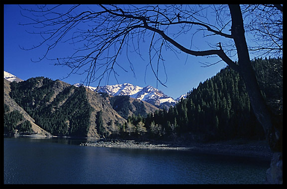 Heaven Pool or Heavenly Lake (Tian Chi) with snow-covered Tian Shan mountains in the distance. Urumqi, Xinjiang, China