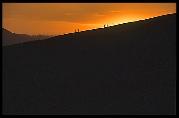 People watching the sunrise on the towering sand dunes at Crescent Moon Lake (Yueyaquan). Dunhuang, Gansu, China