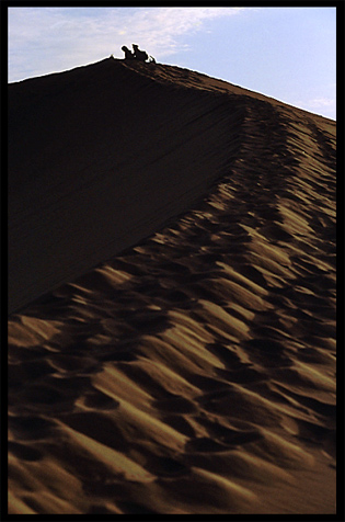 People watching the sunrise on the towering sand dunes at Crescent Moon Lake (Yueyaquan). Dunhuang, Gansu, China