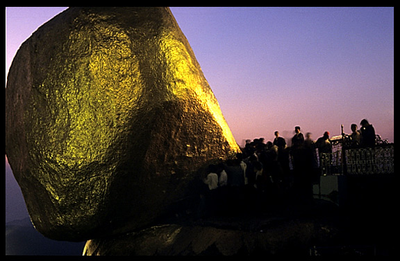 Devotion by adding goldstickers at the incredible balancing boulder stupa in Kyaiktiyo at sunset.