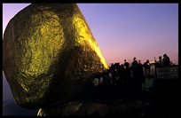 Devotion by adding goldstickers at the incredible balancing boulder stupa in Kyaiktiyo at sunset.