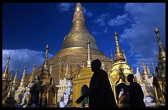 Silhouettes of monks in front of the great golden dome of Shwedagon Paya in Yangon.