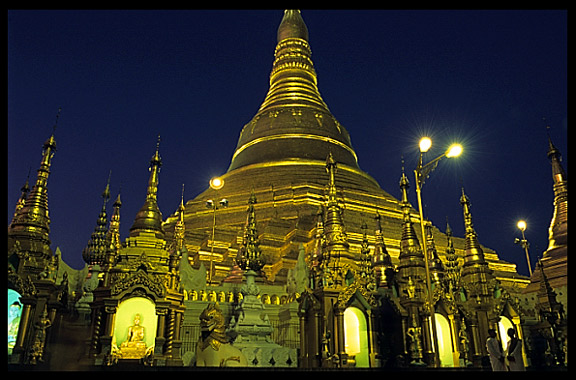 Buddhist nuns standing in front of Shwedagon Paya at night.
