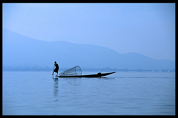 Leg rowing Intha fisherman in sampan on Inle Lake in Shan State.