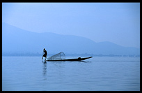 Leg rowing Intha fisherman in sampan on Inle Lake in Shan State.