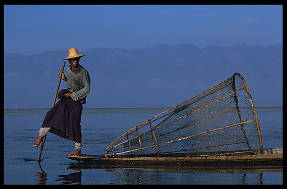 Leg rowing Intha fisherman in sampan on Inle Lake in Shan State.