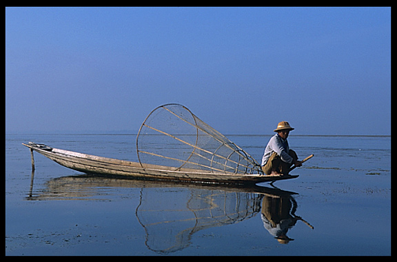 Leg rowing Intha fisherman in sampan on Inle Lake in Shan State.