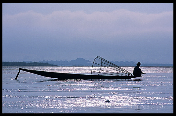 Leg rowing Intha fisherman in sampan on Inle Lake in Shan State.