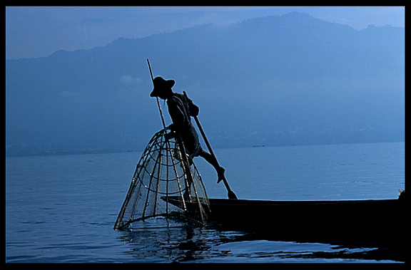 Leg rowing Intha fisherman in sampan on Inle Lake in Shan State.