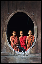 Young monks standing in oval windows of an 18th-century wooden monastery, Shwe Yaunghwe Kyaung.