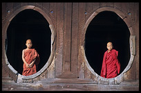 Young monks standing in oval windows of an 18th-century wooden monastery, Shwe Yaunghwe Kyaung.