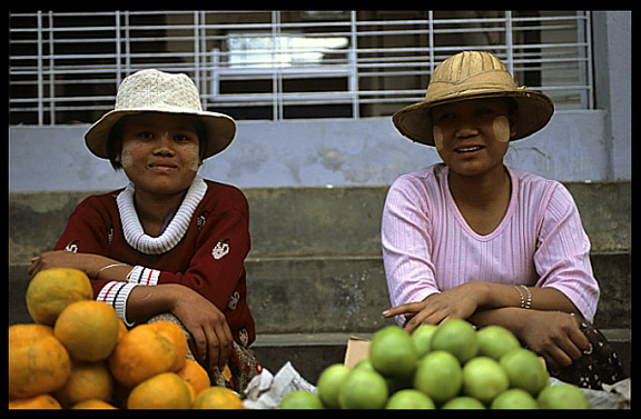 Two Burmese women selling apples and oranges at the Zeigyo (Central Market).