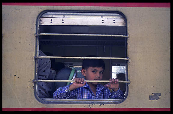 A boy looking out of the window at the train station. Taxila, Pakistan