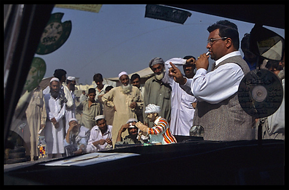 A charlatan tries to sell his "medicines" to Afghan refugees on the Afghan horse market. Peshawar, Pakistan