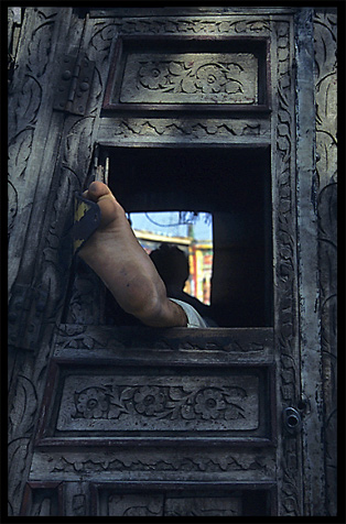 A truck driver taking a nap with his foot outside the wooden door. Peshawar, Pakistan