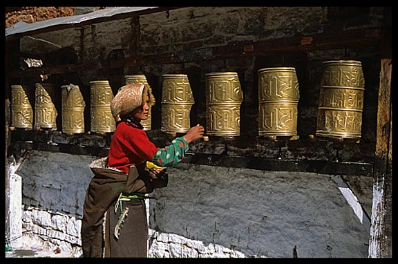 A pilgrim walking the Potala Kora spinning prayer wheels.