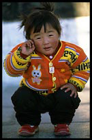 A girl with a Buddha amulet playing on the Jokhang square. Lhasa, Tibet, China