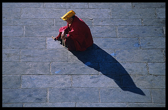 A monk is resting on the Barkhor Square.