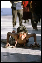 A young Tibetan boy prostrating on the Barkhor Kora. Lhasa, Tibet, China
