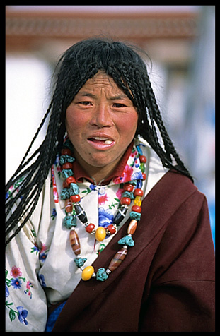 A woman pilgrim eating candy in front of the Jokhang.
