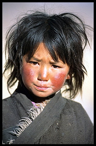 A Tibetan child with red cheeks from the cold, the height and the sun.