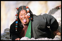 A Tibetan pilgrim squeezes into the deep slices of a cliff face as a means of sin detection. Nam Tso, Tibet, China